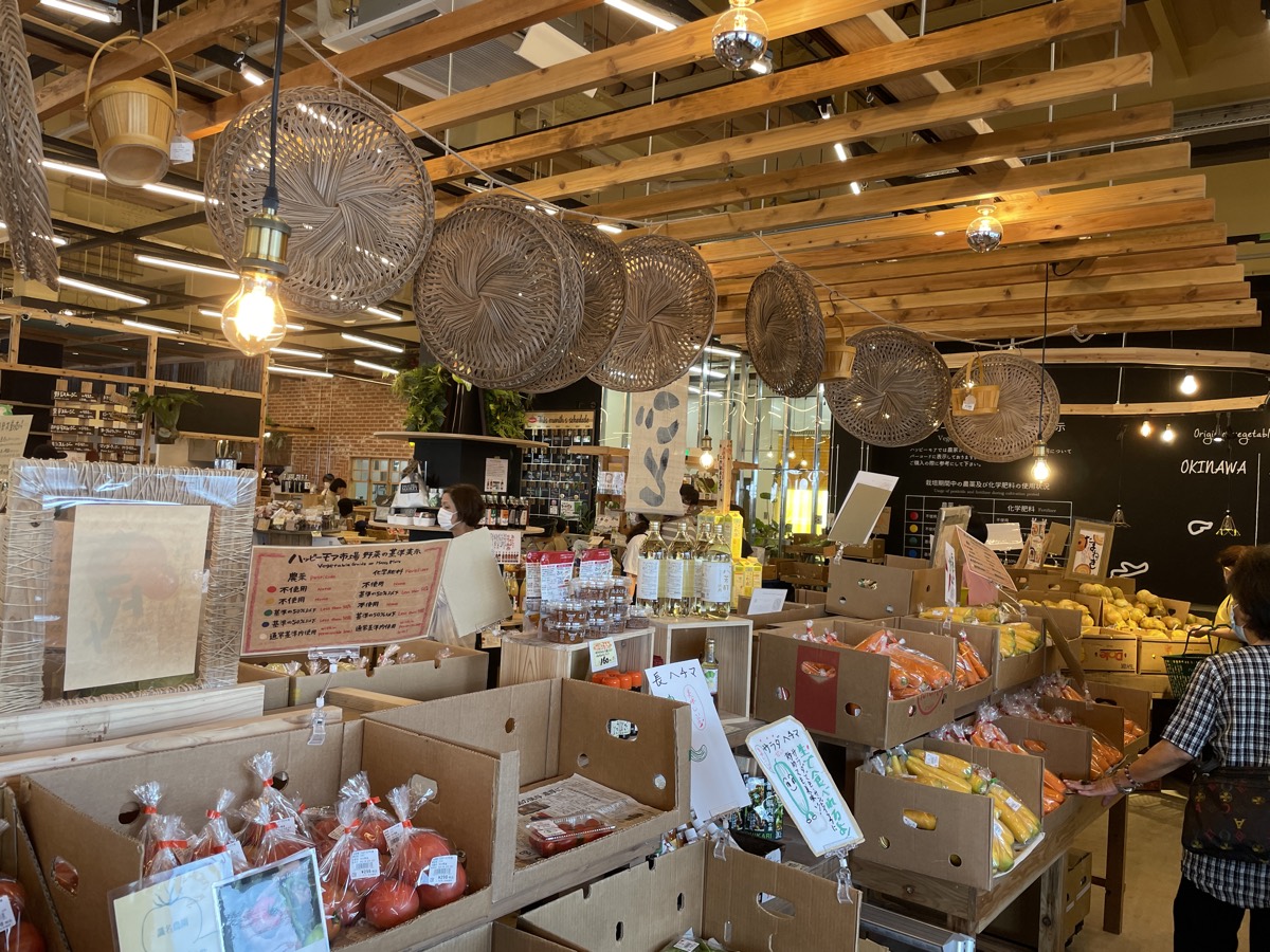 Woven lampshades hanging over crates of vegetables inside Happy More Ichiba