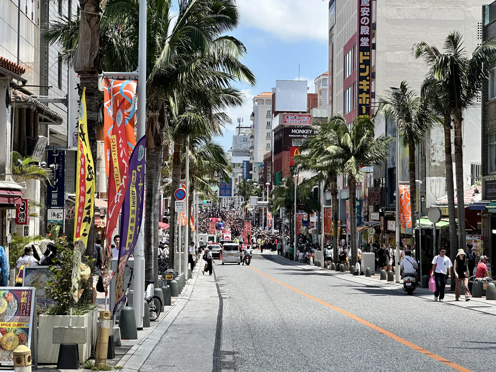 Banners and palms along Kokusai-dori, looking down the street in the afternoon