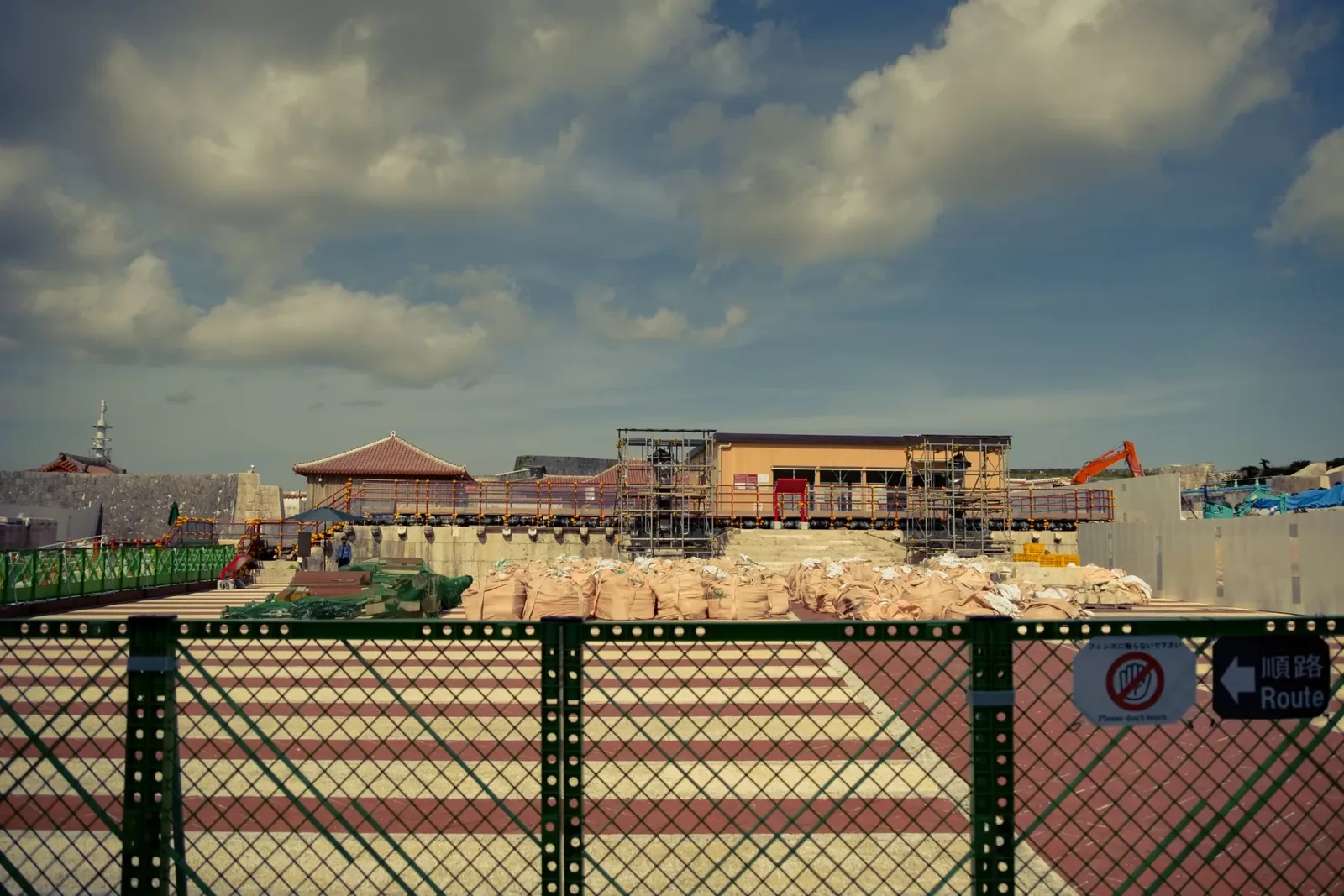 The Shuri Castle rebuild seen over the site hoarding, with surviving red-tiled buildings behind
