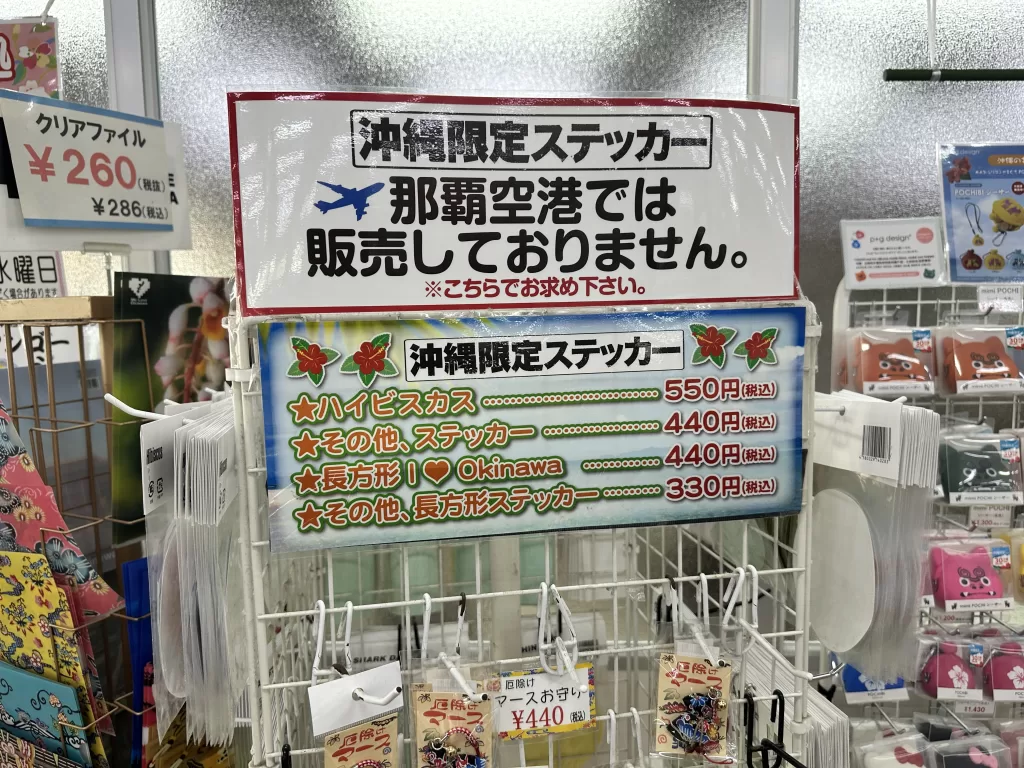 A shelf of Okinawa-only stickers with a notice saying they are not sold at Naha Airport