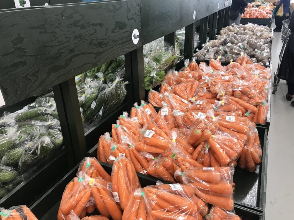 Wooden shelves of carrots, cucumbers and bitter melon at Uru Marche