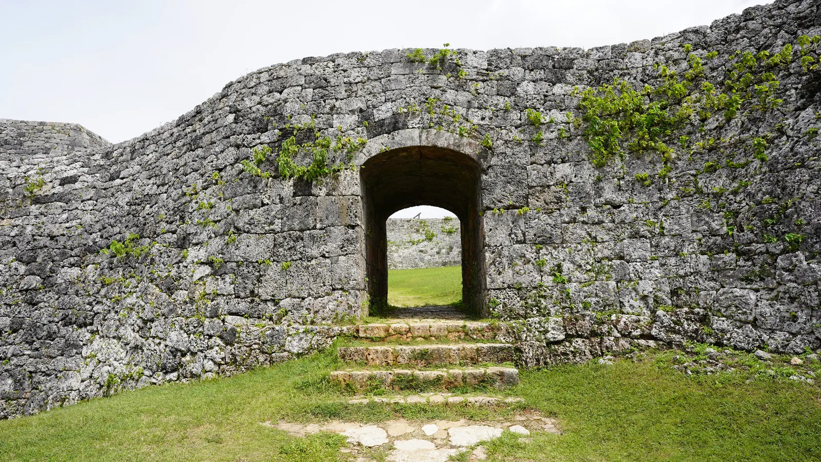 The stone arch gate of Zakimi Castle with steps leading up to it