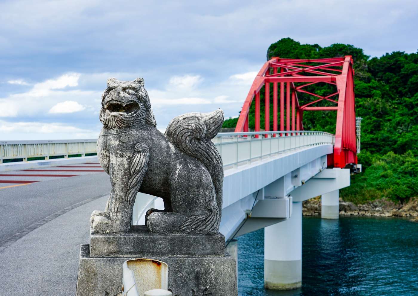 伊計大橋のたもとに置かれたシーサーと、朱色のアーチ橋