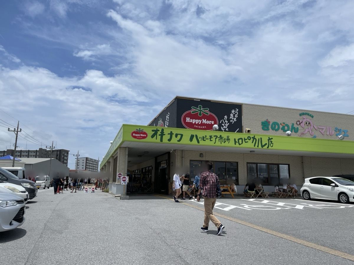 黄緑のひさしとトマトのロゴが目印の、ハッピーモア市場トロピカル店の外観